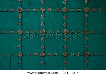 Fragment of an old green metal door with rosettes and stripes - vintage background, pattern