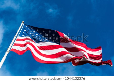 huge perfect American Flag waving in the breeze with the perfect blue sky background. A patriotic symbol of the United States of American one nation under god with liberty and justice for all