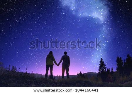 Night landscape with loving couple. Night sky with Milky Way stars in mountain landscape