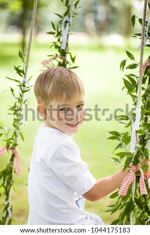 Bright summer berry party in park. Boy on the swing