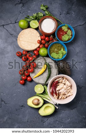 Home made tortillas served with chicken avocado, tomatoes salsa verde and red salsa, lime, chilies, yogurt and coriander over a stone board. Top View