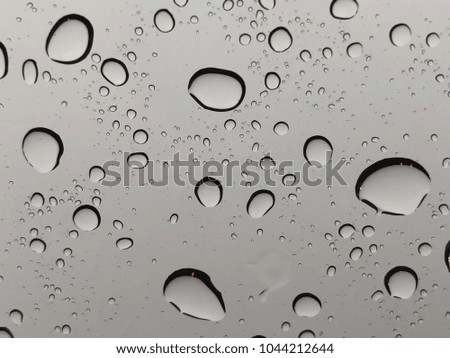 Raindrops on car window with sky background.