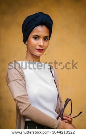 Portrait of a fashionable, stylish, young, attractive and elegant Muslim woman wearing a blue headscarf (turban, hijab) in a studio. She is elegantly dressed in business casual in a studio.