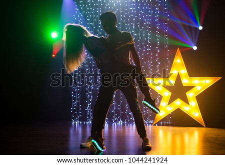silhouette couple of loving young man and woman dancing and having fun in a nightclub at a party
