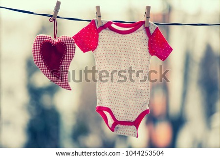 Baby clothes and a red heart hanging on the clothesline