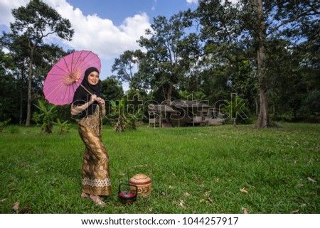 Fashion portraiture of young beautiful malay woman wearing modern kebaya with pink umbrella and traditional food basket. 