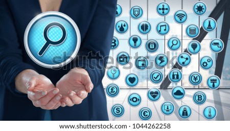 Digital composite of Magnifying glass search icon with various apps and Businesswoman with hand palm open in city office