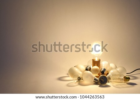 A functional lamp that lights and illuminate in a pile by broken old light sources of different kinds ready to be recycled. Royalty-Free Stock Photo #1044263563
