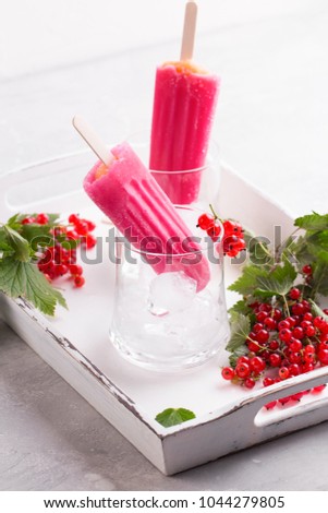 Pink berry popsicle with red currant on vintage background.