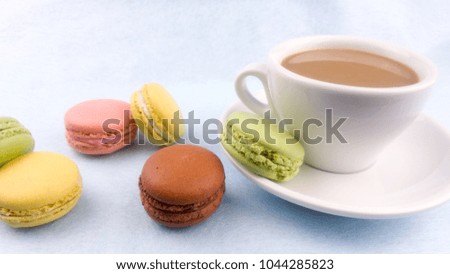 Color sweet macaroons or macaron on white plate with coffe cup on pastel background.