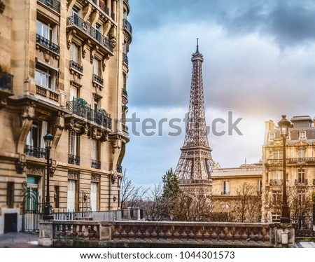 small paris street with view on the famous paris eiffel tower on a cloudy rainy day with some sunshine Royalty-Free Stock Photo #1044301573
