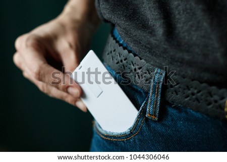Close Up woman hand grabbing a white card in jeans pocket on dark background, smart card concept, mock up