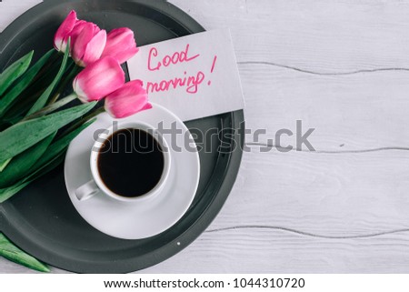 Tulips with a cup of coffee and the text "good morning" on a wooden table top view