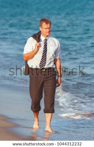 Young businessman walking on th e beach after the work time