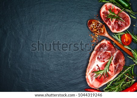 Steak on the bonewith cherry tomatoes, hot pepper and herbs. Raw beef steaks with spices and rosemary.