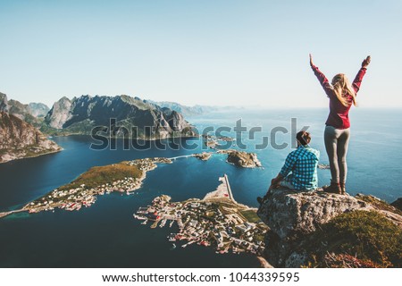 Couple family traveling together on cliff edge in Norway man and woman lifestyle concept summer vacations outdoor aerial view Lofoten islands Reinebringen mountain top Royalty-Free Stock Photo #1044339595