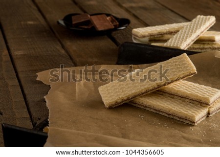 Chocolate waffers on the parchment and a wooden background