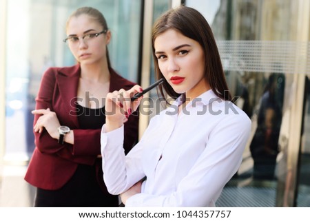 two beautiful young women in business clothes on the background of a modern building