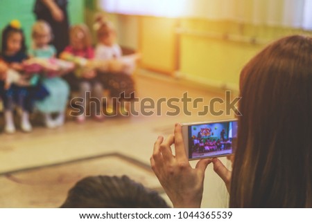 woman taking a picture of children on the phone in kindergarten