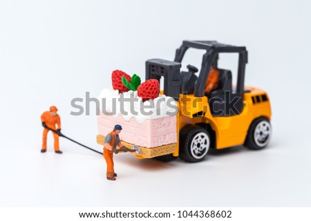 Miniature people on cake with strawberry on top, cooking and decoration concept. The concept of a collective solution to any problem. Close-up view. 