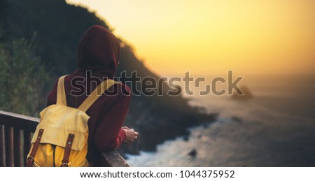 Hipster hiker tourist with backpack looking of amazing seascape sunset on background sea, girl enjoying ocean horizon, panoramic sunrise, traveler relax holiday concept, sunlight view in trip vacation