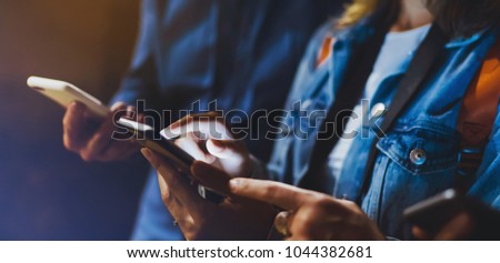 Bloggers together pointing finger on screen smartphone on background bokeh light in night city, group adult hipsters friends using in hands mobile phone closeup, street online wi-fi internet concept