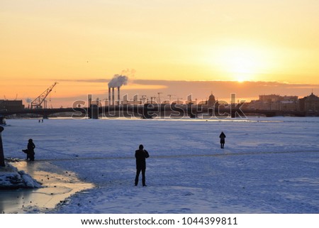 People take pictures of the Annunciation bridge at sunset in winter in Saint-Petersburg
