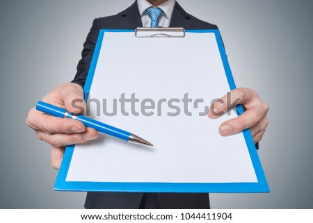 Man is showing and offering blank white paper in clipboard with pen.