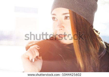 Beautiful girl in a black mink coat in a winter street. Toned photo