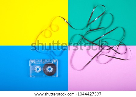 A cassette tape on a colored table with a tangled ribbon. View from above. 