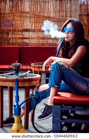 Young hot trendy girl smoking hookah outside Royalty-Free Stock Photo #1044460963