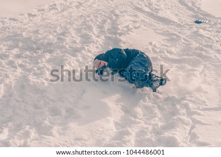 The boy is lying around and playing in the snow on the hill, winter snow frosty weather