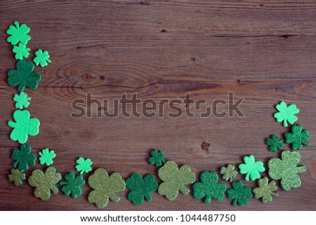 Blackboard with four-leaved clover. St Patricks Day corner border of shamrocks over a rustic wood background. Free space. St. Patrick's Day lucky charms background. 