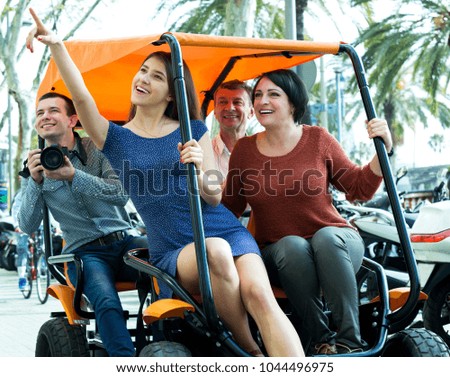 Attractive couple with adult children sitting in grand tour electric and taking pictures of Europenian city