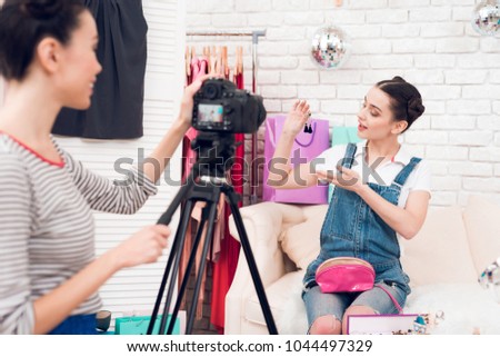 Two fashion blogger girls in jeans and shirt with skirt hold up colorful jewelry with one girl behind camera.
