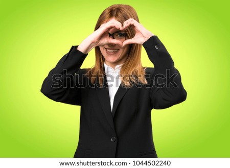 Young business woman making a heart with her hands on colorful background