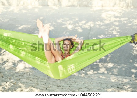 young happy woman in a bright yellow hammock on the beach