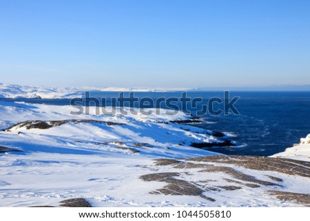Arctic Ocean, winter time, snow shore, Russia, landscape of beautiful wild nature of north sees. Beautiful snow winter ice and cold landscape, picturesque view with mountains on horizon, sky clouds