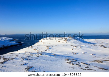 Arctic Ocean, winter time, snow shore, Russia, landscape of beautiful wild nature of north sees. Beautiful snow winter ice and cold landscape, picturesque view with mountains on horizon, sky clouds