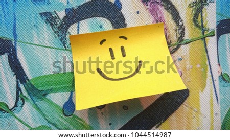 Yellow sticky note with drawn smiley on colorful background