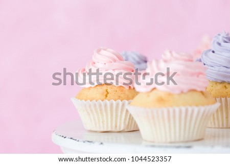 Violet and pink cupcakes on shabby shic stand on pink pastel background. Sweet beautiful decorated with buttercream cakes  for horizontal banner or greeting card.