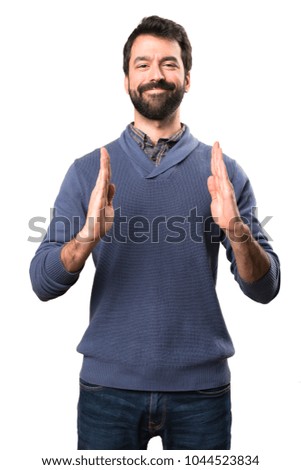 Handsome brunette man with beard holding something on white background