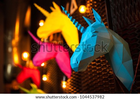 Blue and colorful paper unicorn on dark background. Origami toy. Origami pegasus. Head of unicorn of paper.