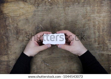 male hands holding a white blank sheet of paper on the background of wooden texture table