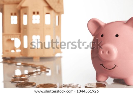 Pink piggy bank, coins trail and a house isolated on white background, Real estate or home savings