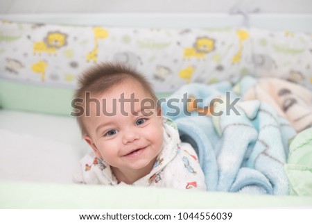 Blue-eyed baby boy lying in crib
