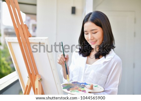 Concept Artist Beautiful girl. Beautiful women are creating art. Beautiful woman is painting happily. Young artist painting outside the house.