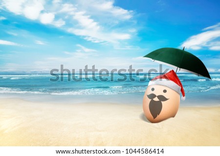 Egg with santa hat in the beach with blue ocean background