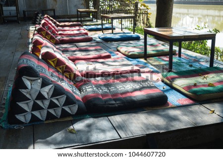 Serene asian thai river cafe with table and mats, stock photo