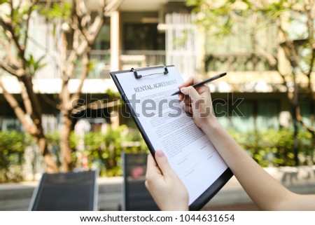 close up portrait of woman hands signing rental agreement on background of leasing office apartments. girl travel and rent short term condo in america. concept of traveler looking for place to live